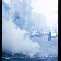 Color slide of used firecrackers still smoking on a street.