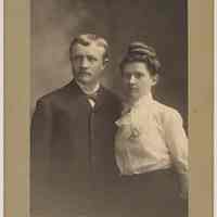 Sepia-tone photo of young man & woman posed in photo studio, Hoboken or Jersey City, n.d., ca. 1910-1920.