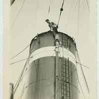 B+W photo of a shipyard worker near the top of a funnel on an unidentified vessel, no date, ca. 1940.