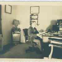 B+W photo of a man in an office, location and date unknown.