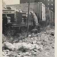 B+W photo of trash near fence belonging to Diamond Reo of Hudson County, 8th & Madison Sts., Hoboken, no date, ca. 1970-1980.