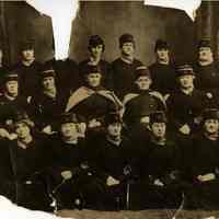 Sepia-tone group photo of American Red Cross volunteers posed in a studio, Hoboken, n.d., ca. 1918-1920.
