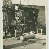          B+W photo print as postcard view of shipyard riggers with propeller of an unidentified vessel in drydock, no date, ca. 1940. picture number 1
   