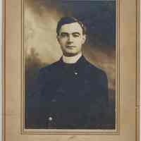 Sepia-tone photo of an unidentified man in clerical dress posed in photo studio, Hoboken, no date, ca. 1900.