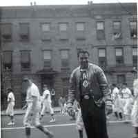 B+W photo of a Police Athletic League coach and baseball team marching on Washington Street, Hoboken, no date, ca. 1955.