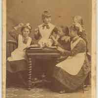 Carte-de-visite of 5 girls posed playing school(?), Hoboken, n.d., ca. 1880-1885.