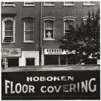 B+W photo of Hoboken Floor Covering truck & store front on Washington St., Hoboken, no date, [1976].