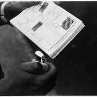 B+W photo of a person about to light a stack of Cappiello ticket handbills on election day, Hoboken, [June 11, 1985].