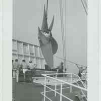 B+W photo of a 5-blade propeller being moved or placed on an upper deck of an unidentified vessel, no date, ca. 1950-1960.