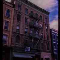          Color slide of eye-level view of brick façade, cornice, pediments and fire escape at 202-204 Hudson between 2nd & 3rd showing a grocery store and the India Bazaar storefronts picture number 1
   