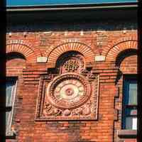 Color slide of close-up view of clockface roundel and brick arches on the facade of the Hoboken Land building at 1 Newark