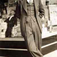 Sepia-tone photo of a man posed in front of the exterior of Baron