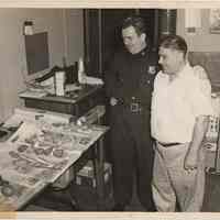 B+W photo of a police officer and Joseph "Biggie" Yaccarino admiring sandwiches at unnamed precinct house, Hoboken, no date, circa 1945-1950.