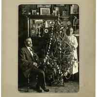 Sepia-tone photo of man (Anthon Van Der Weil?) & woman (wife?) in parlor with Christmas tree, probably Hoboken, N.J., ca. 1920 or earlier.