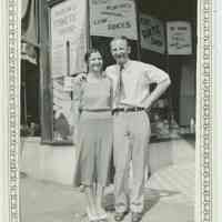 B+W photo of a woman and man posed in front of the exterior of Baron