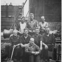 Sepia-tone group photo of eight dry dock workers posed on pier at Hoboken shipyard, no date, ca. 1925-1935