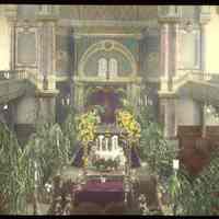 Lantern slide, color, of a synagogue interior with floral decorations, used for promotional display in Hoboken, no date, ca. 1920.