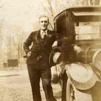 Digital image of photo of a man in suit leaning against an automobile, no place (probably Hoboken), no date, circa 1915-1920.