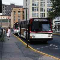 Color photograph of 2 Red Apple N.Y.-Hoboken buses at Hudson Pl. bus stop near PATH entrance, Hoboken, Aug. 16, 1995.