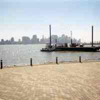 Color photo of view southeast from Frank Sinatra Park amphitheather of barge & small boat, Hoboken, n.d., ca. 2002-2004.