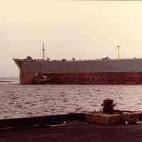 Digital scan of color photo of New York Harbor with a vessel and tugboat, no date, circa 1970-1980.