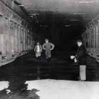 B+W photo of 3 men inside flooded Lincoln Tunnel during construction on N.Y. side, Jan. 25, 1956.