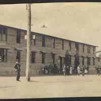 Digital image of photo of exterior view of military barracks with some people (mostly civilians), no place, no date, circa 1900-1910.