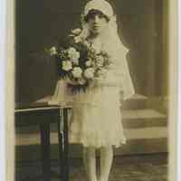 Sepia-tone photo of girl posed in studio with church interior backdrop, Hoboken, n.d., ca. 1910-1925.