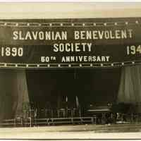 B+W photo of a hall with Slavonian Benevolent Society 50th Anniversary banner, decorated by United Decorating Company of Hoboken, Hoboken, 1940.