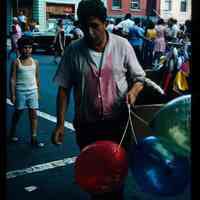 Color slide of a man holding balloons.