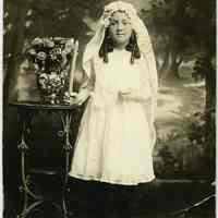 Sepia-tone photo of girl with candle, catechism and rosary posed in studio, Hoboken, n.d., ca. 1918-1930.