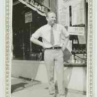 B+W photo of a man posed in front of the exterior of Baron