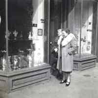 B+W photo of two women looking into the storefront of Keil