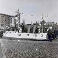 Sepia-tone photo of battleship float, North German Lloyd Line headhouse area, Hoboken, n.d., ca. 1915-1916.