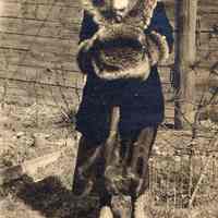 Digital image of photo of a woman posed outdoors with fur trimmed coat and muff probably in a backyard, no place (Hoboken?), no date, ca 1915-1925.