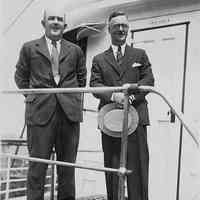 B+W photo of 2 businessmen in suits standing in front of door to pilot house on unidentified vessel, Hoboken, no date, ca. 1940.