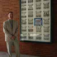 Color photos, 3, of artist Robert Burczy posed next to display marquee in Hoboken Historical Museum walkway, May 4, 2006.