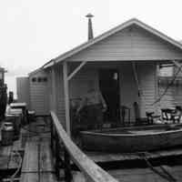 B+W photo of Frank Jennes (?) on floating shack docked at 4th St. & Hudson River, Hoboken, n.d., ca. 1940s?.