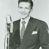 Black-and-white publicity photo of a young Frank Sinatra in a dark jacket & tie at a CBS microphone, no place, no date, ca. 1940-45.