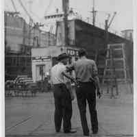 B+W photo of two men, probably supervisors, near head of Pier 3, at Bethlehem Steel Shipyard, Hoboken Division, no date, ca. 1940.