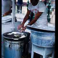 Color slide of a man frying food at a street fair.