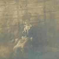 Sepia-tone photo of Anna Rivlon seated in a rocker in the backyard of 716 Bloomfield St., Hoboken, no date, ca. 1890.