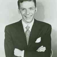 Black-and-white photo of a young Frank Sinatra in a dark jacket & tie, no place, no date, ca. 1940-45.