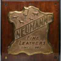 Bronze plaque [company logo]: Neumann Fine Leathers Since 1863. N.d., ca. 1930-1960.