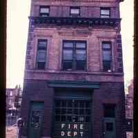          Color slide of eye-level view of fire station façade, cornice, quoins and frieze reading 