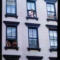 Color slide of people looking out of the windows of a brick building.