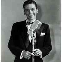 Black-and-white publicity photo of a young Frank Sinatra in black dinner jacket & bowtie at microphone, no place, no date, probably Dec., 1942.