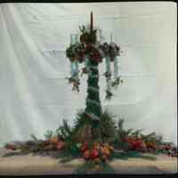 Lantern slide, color, of a tall Christmas centerpiece with evergreens, garland & candle,used for promotional display,Hoboken, no date, ca. 1920.