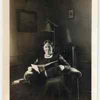          45: loose photo; woman seated in chair with magazine; note slippers
   