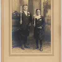 Sepia-tone photo of 2 boys formally dressed; holding candles, rosaries & catechisms, Hoboken, n.d., ca. 1900-1910.